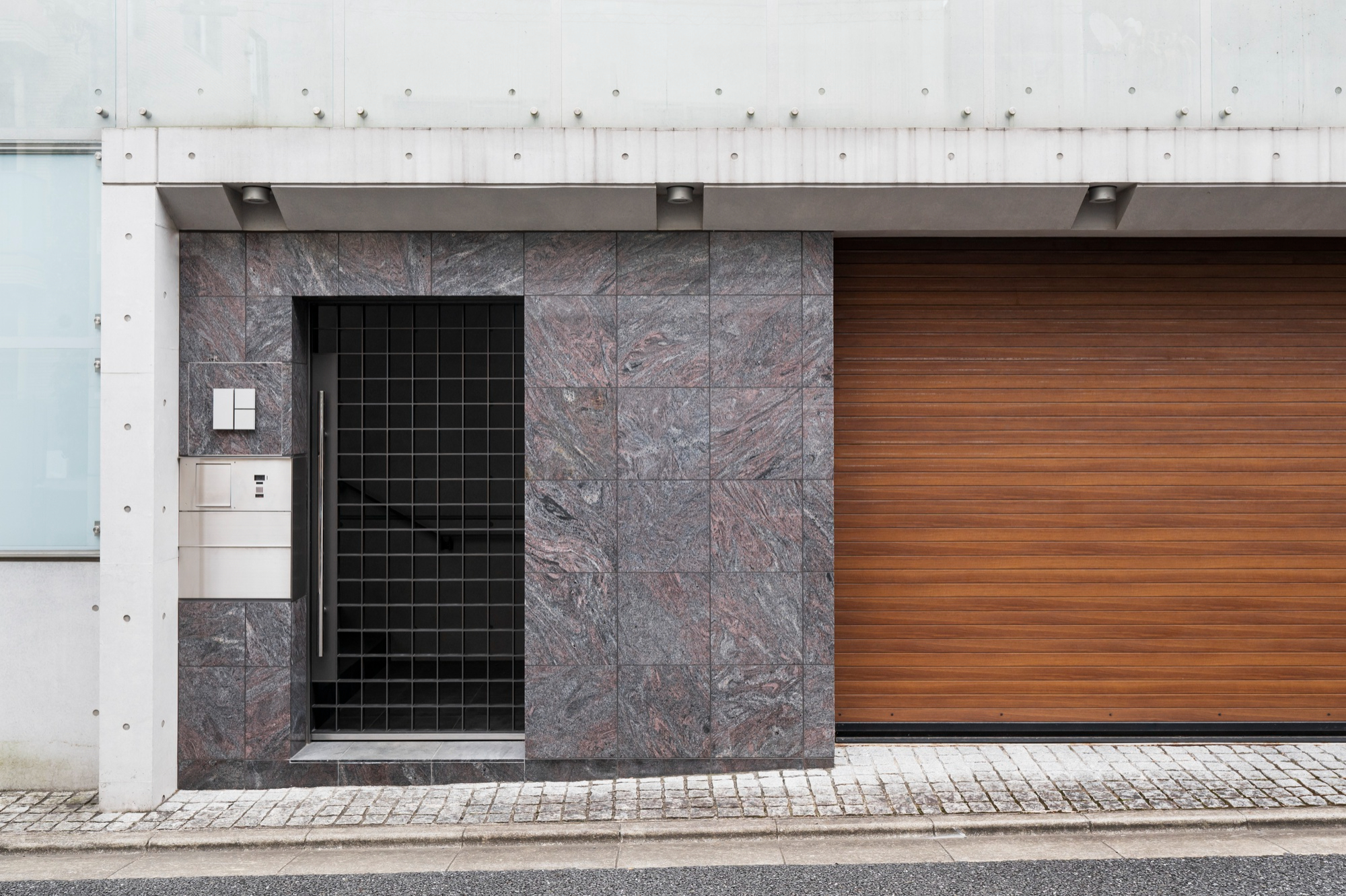 Fachada de acceso residencial con portón de madera y herrajes de precisión